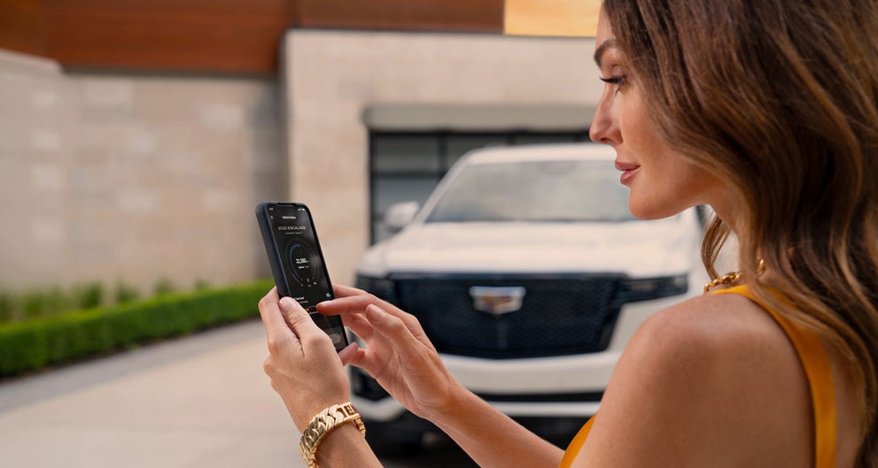 lady checking her mobile with a Cadillac vehicle background | McGuire Cadillac in Woodbridge NJ